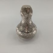 A white metal baluster shaped water flask with swirling and chased decoration, matching goblet,