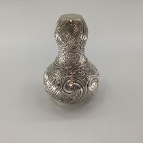 A white metal baluster shaped water flask with swirling and chased decoration, matching goblet,