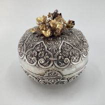 A white metal middle eastern style , circular casket with raised floral decoration, gilt floral