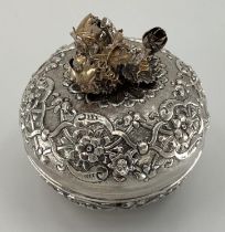 A white metal Middle Eastern style circular casket with raised decoration, gilt floral finial and
