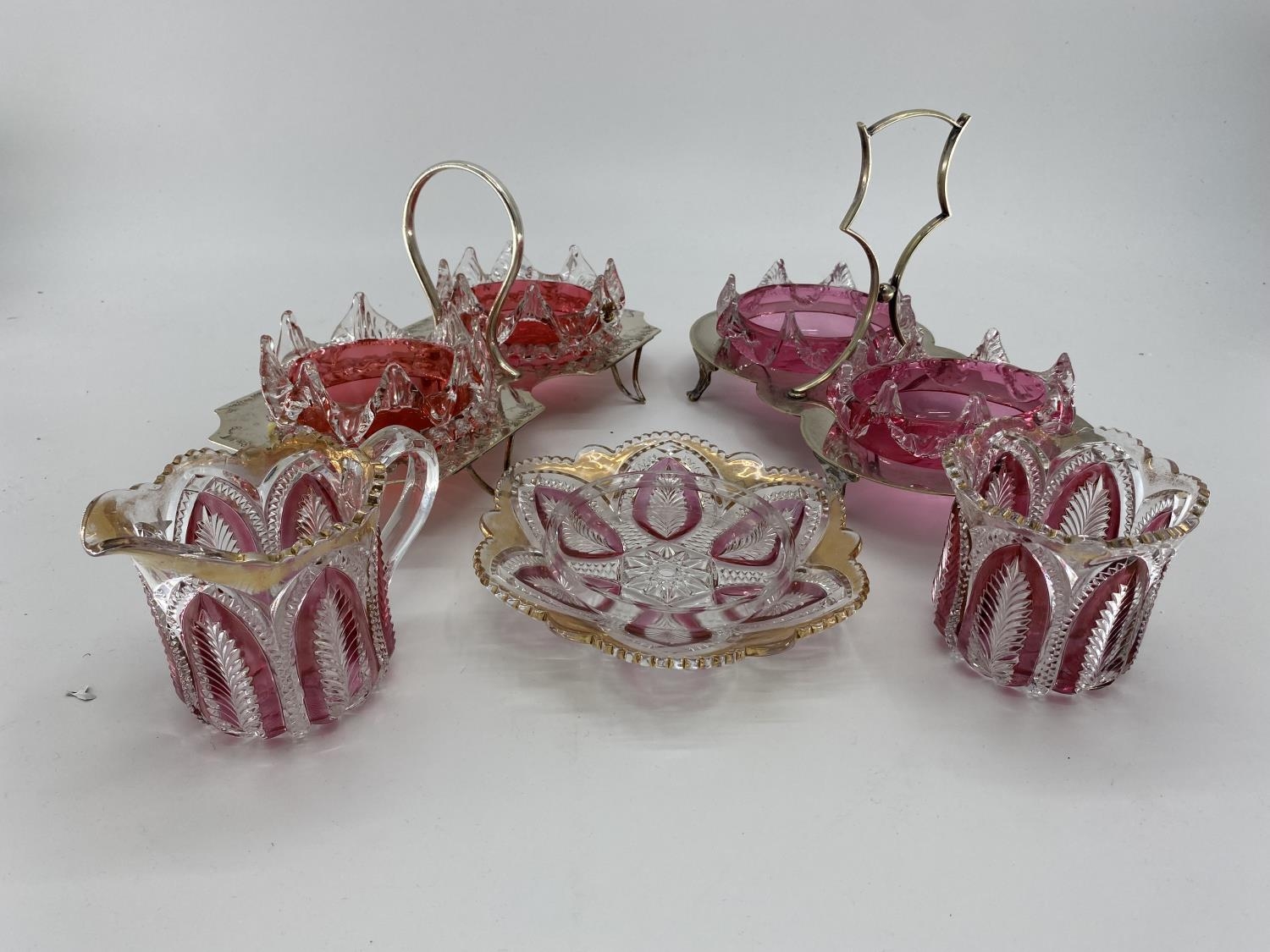 Two cranberry glass and white metal sweet meat serving platters, and two flash cut glass jugs and