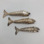 Three graduated white metal articulated fish ornament, with glass enamel eyes marked Mexico,