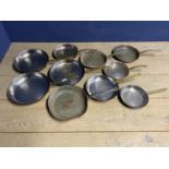 A collection of brass and copper frying pans and skillets, all stamped La Gavroche on the handle.