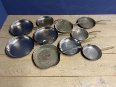 A collection of brass and copper frying pans and skillets, all stamped La Gavroche on the handle.