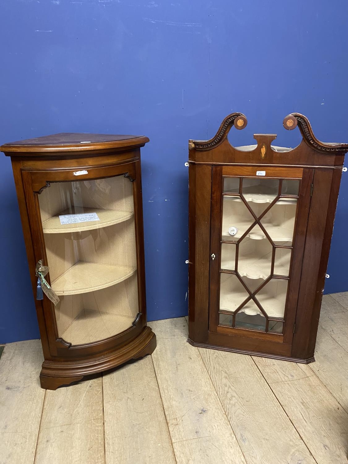 A corner display cabinet with bow front glazed door and key