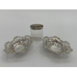 A pair of sterling silver pierced oval dishes, and a silver topped glass dressing table item
