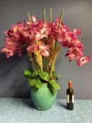 A large impressive faux flower arrangement, purple orchids, with bamboo sticks and foliage, in large