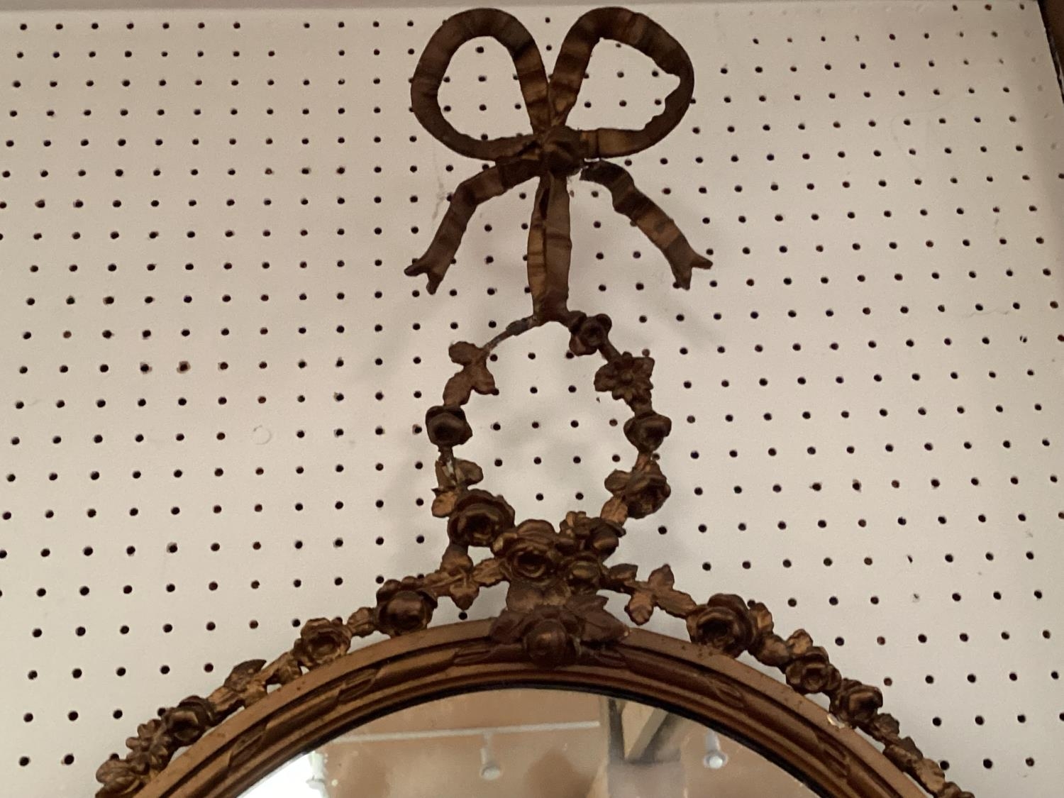 A decorative oval gilt frame wall mirror, with ornate carved flower and bow finial to top, and swags - Image 3 of 3