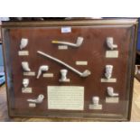 A collection of reproduction traditional clay pipes in a glazed display frame