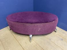 A modern oval shaped stool, upholstered in a purple velvet fabric and chrome legs, with much wear