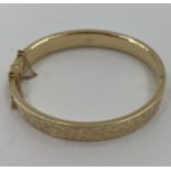 A 9ct gold bangle bracelet with chased decoration, 12.4g