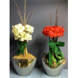 Two faux flower arrangements, a white and red amaryllis, in contemporary mirrored oval planters, set