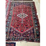 An antique rug, frayed at ends, 130 x 203cm; red ground with geometric design