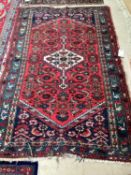 An antique rug, frayed at ends, 130 x 203cm; red ground with geometric design