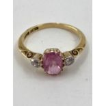 An 18ct gold fancy pink sapphire and diamond ring, central oval free cut sapphire with old brilliant