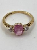 An 18ct gold fancy pink sapphire and diamond ring, central oval free cut sapphire with old brilliant