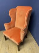 A Georgian high wing backed arm chair upholstered in an orange velvet style fabric on mahogany