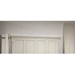 A contemporary white painted wooden double bed, with panelled high headboard and panelled foot