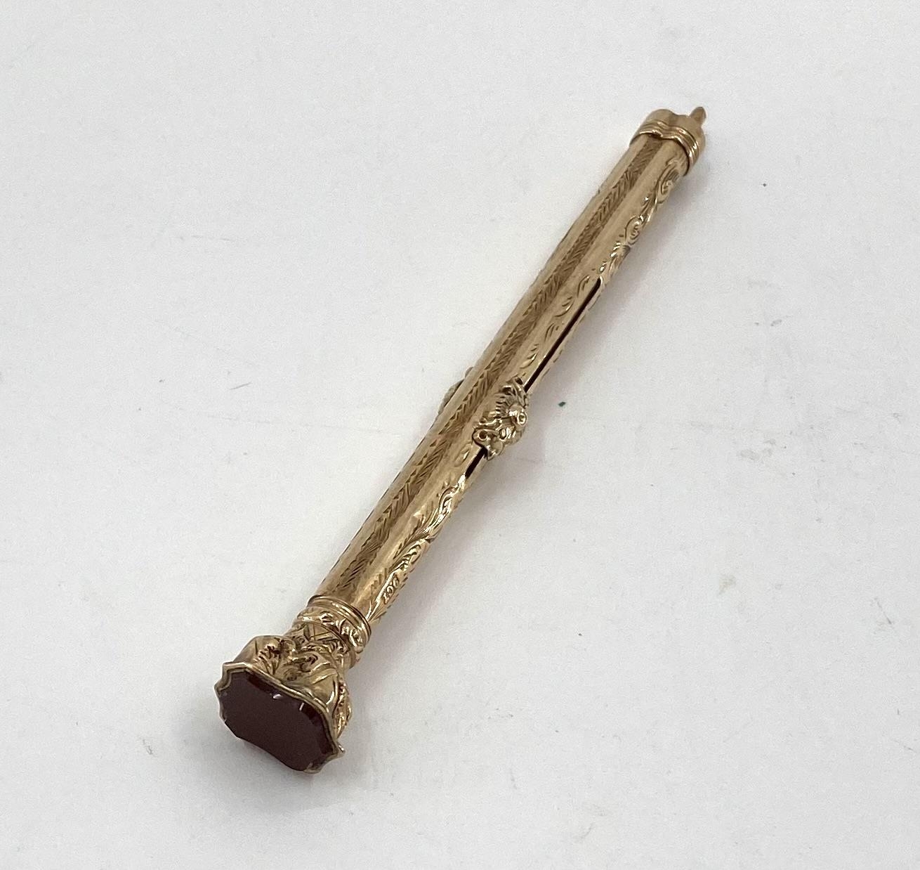 A 9ct gold propelling pencil with chased decoration, and shield shape carnelian top, 14.2g