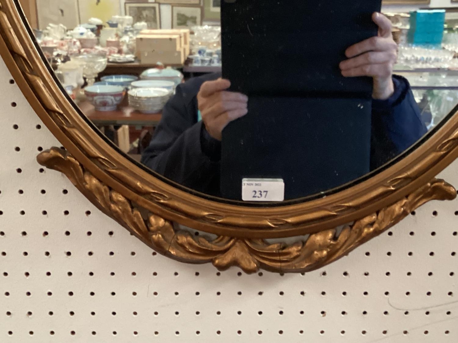 A decorative oval gilt frame wall mirror, with ornate carved flower and bow finial to top, and swags - Image 2 of 3