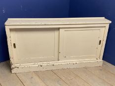 Vintage style cream painted low side cupboard, the sliding doors opening to reveal shelves