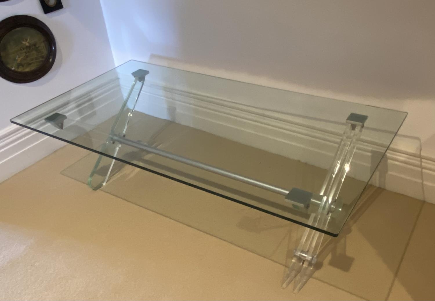 A Contemporary low glass table with X frame base, 135cmL x 70cmW x 41cmH