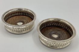 A similar pair of Georgian sterling silver wine bottle coasters with tu