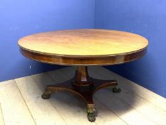 A good Regency mahogany and rosewood circular snap top dining table, with brass edgings, on an