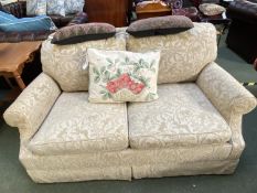 A two seater sofa, upholstered in a cream fabric with patterns of monkeys