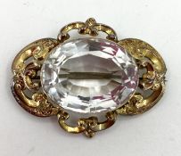 An aquamarine / pale beryl yellow metal Victorian brooch, scrolling setting with oval free cut