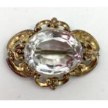 An aquamarine / pale beryl yellow metal Victorian brooch, scrolling setting with oval free cut