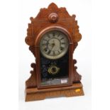 An early 20th century American gingerbread type mantel clock, the silvered dial showing Roman