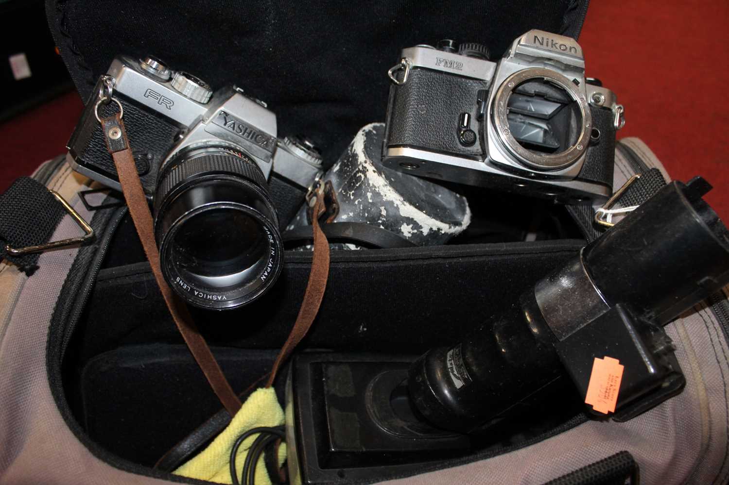 A camera bag and contents to include Yashica FR 35mm SLR camera with lens, Nikon FM2 camera body