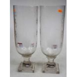 A pair of contemporary glass hurricane lamps, each with star-cut decoration and standing upon a