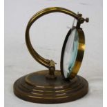 A 20th century brass table magnifier on a circular stepped plinth, height 20cm