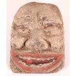 A limestone head, carved as a male face with polychrome decorated mouth and eyes, 22 x 17cm.