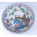 A Chinese Republic period stoneware charger, enamel decorated with peacocks amidst flowering