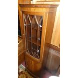 A contemporary mahogany narrow bowfront bookcase, having glazed upper door over panelled lower