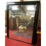 A large circa 1900 and later black painted over mantel mirror, having raised stylised flower head