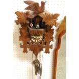 A carved and stained softwood cuckoo wall clock, with three weights and pendulum