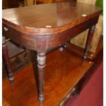 An early 19th century mahogany and ebony strung round cornered fold-over card table, having a