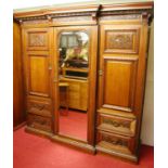 An imposing late Victorian floral relief carved oak triple wardrobe, of breakfront form, having
