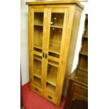 A contemporary light oak double door glazed display cabinet, having twin short lower drawers,