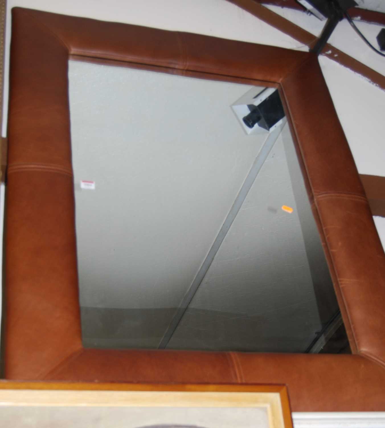 A modern wall mirror in tan leatherette surround 118x88cm