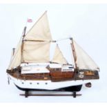 A scratch-built wooden model of a twin mast sailing boat, comprising of black and white painted hull