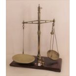 A set of early 20th century Avery brass beam scales, mounted upon a mahogany plinth, h.75cm,