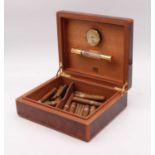 A 20th century burr walnut humidor containing a variety of loose cigars, and a cigar cutter, width