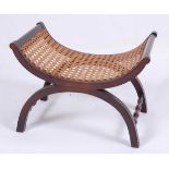 In the manner of Liberty & Co - a circa 1900 beech X-framed stool, having a cane seat with