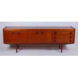 A 1960s teak long sideboard by Stonehill Furniture, having four cupboard doors and three drawers,