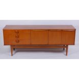 A 1960s teak long sideboard, having three drawers with circular button shaped handles, twin cupboard